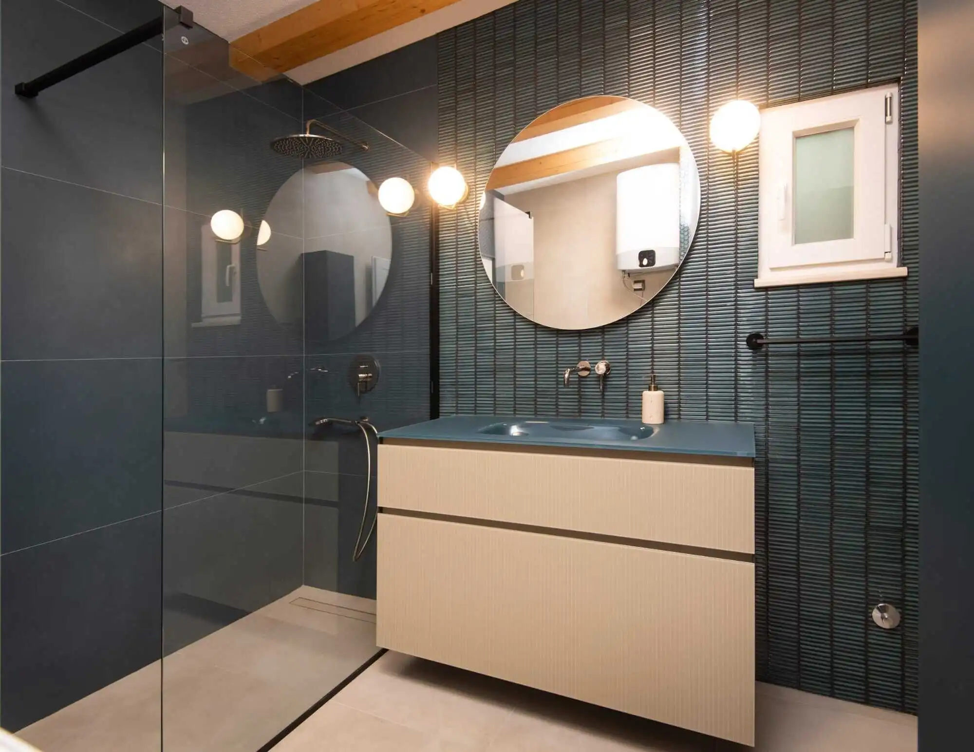 Modern Bathroom with Blue Tiles and Round Mirrors Modern bathroom featuring blue tiled walls, two round mirrors, and contemporary lighting fixtures.