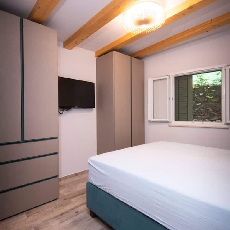 Bright bedroom with minimalist design and wooden ceiling beams in a high-end Split neighborhood.
