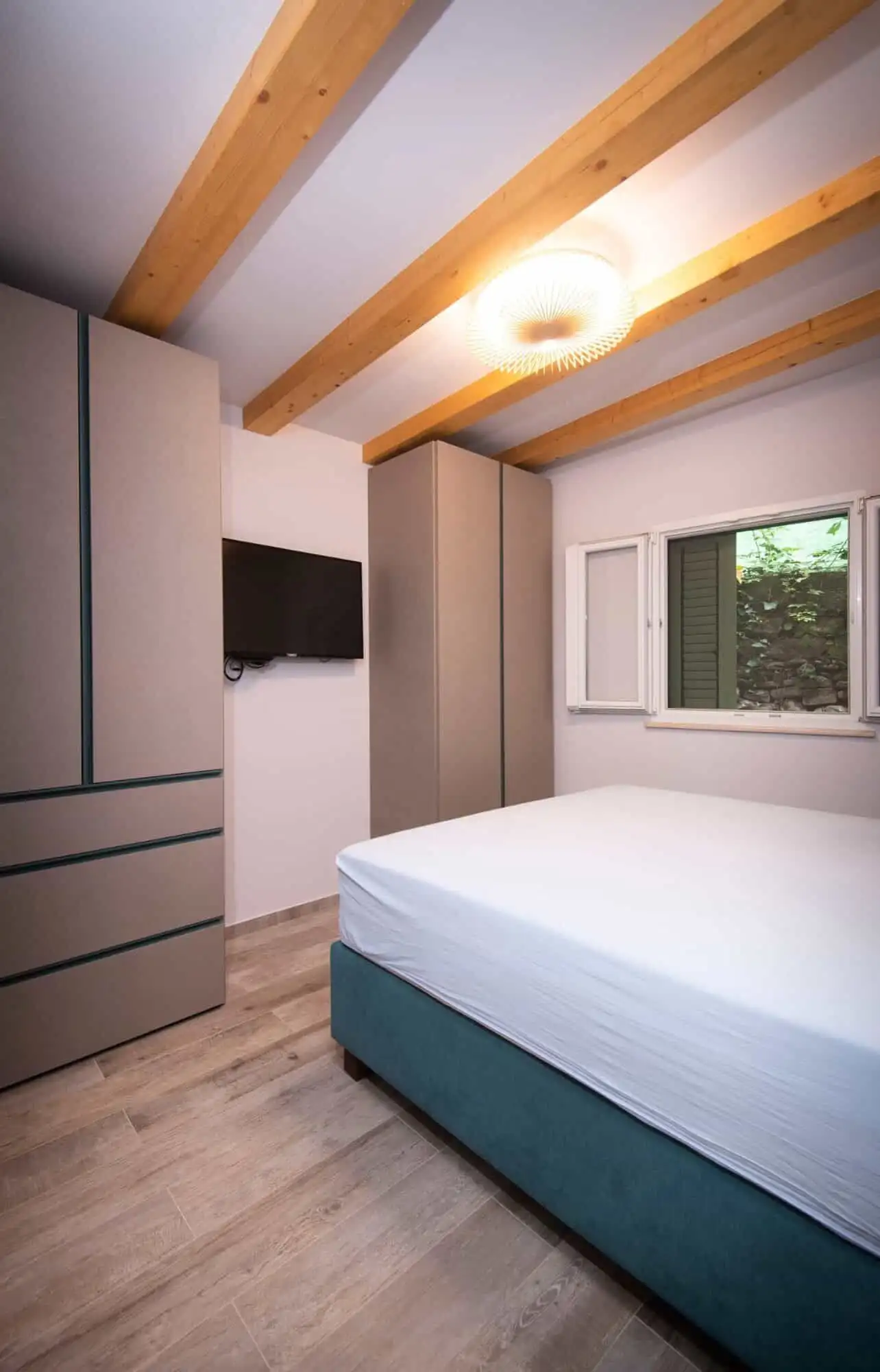 storey bedroom in exclusive Split area Bright bedroom with minimalist design and wooden ceiling beams in a high-end Split neighborhood.