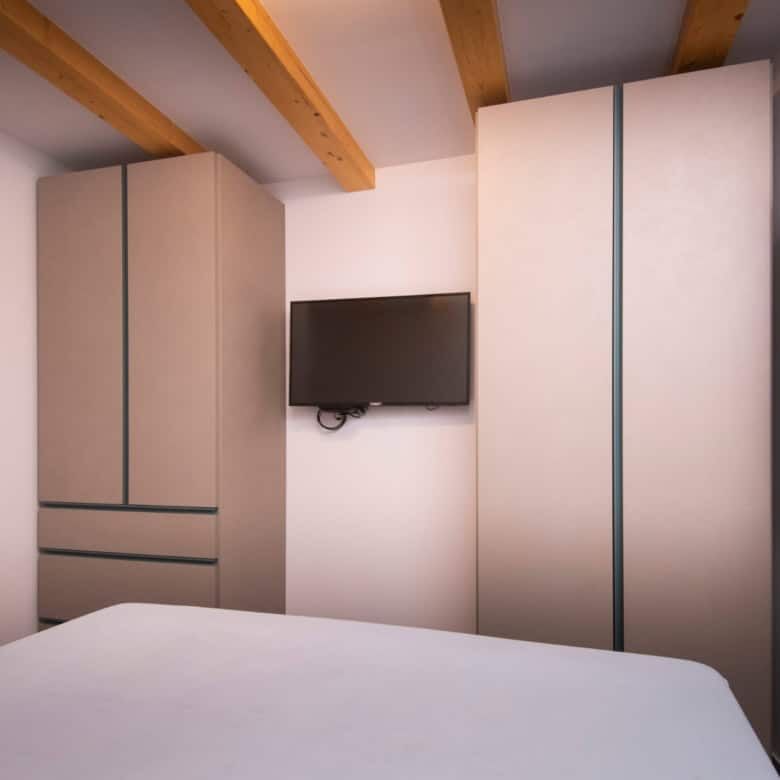 Modern bedroom with built-in wardrobes and a wall-mounted TV in a high-end Split home.