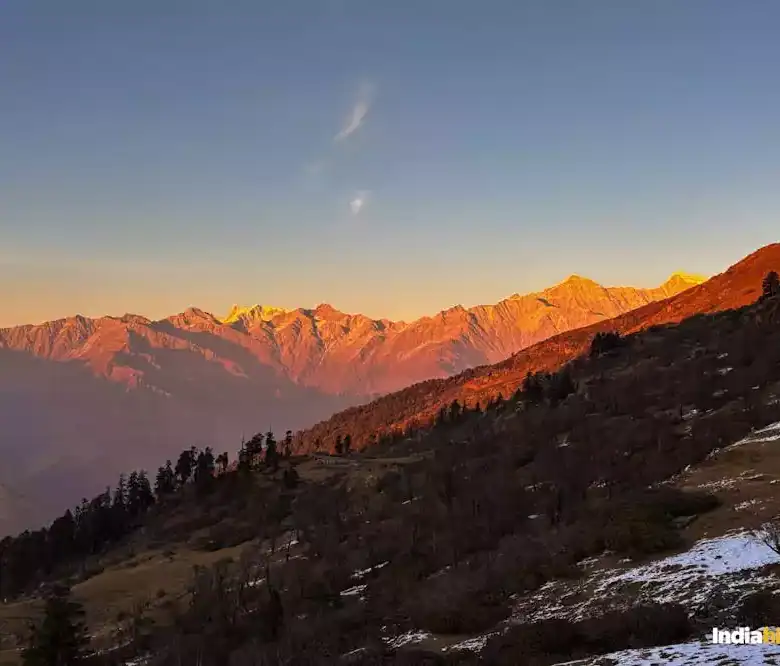 Mountain landscape at sunset with colorful sky and distant peaks.