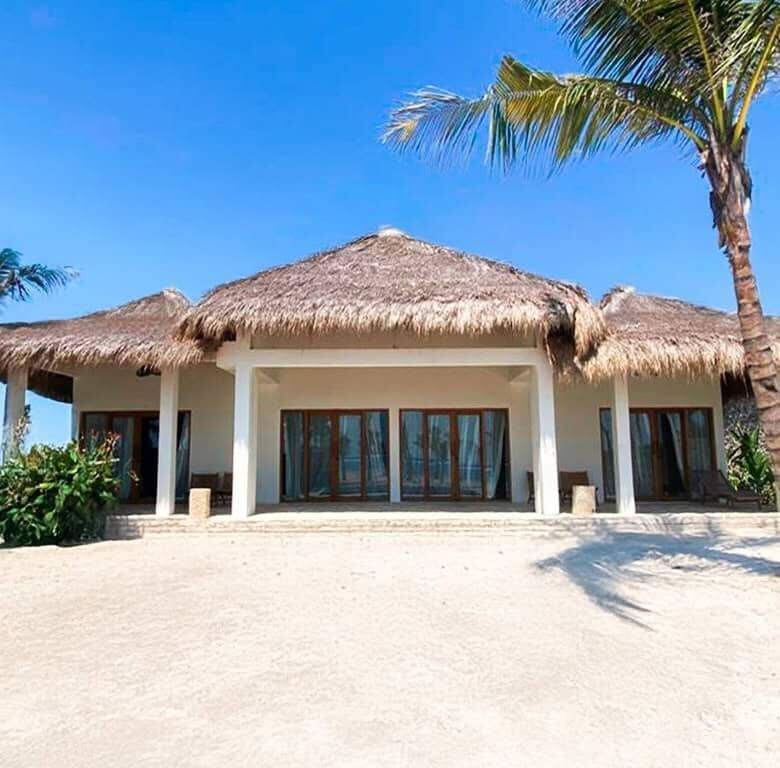 Eco-luxury beachfront villa in Sumba with thatched roof and tropical surroundings.