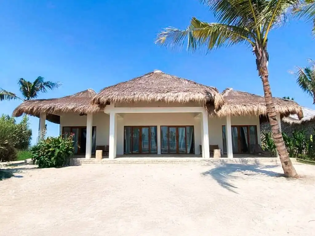 Eco-luxury beachfront villa in Sumba with thatched roof and tropical surroundings.