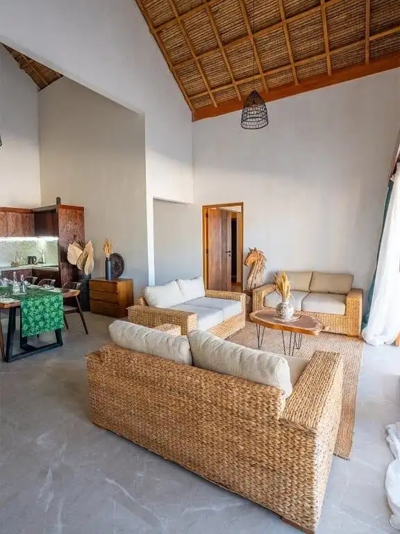 Luxury beachfront villa interior with natural woven furniture and high vaulted wooden ceiling.
