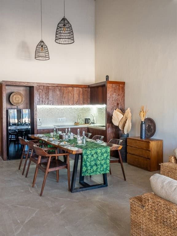 Elegant dining space with wooden furniture, modern lighting, and tropical decor.