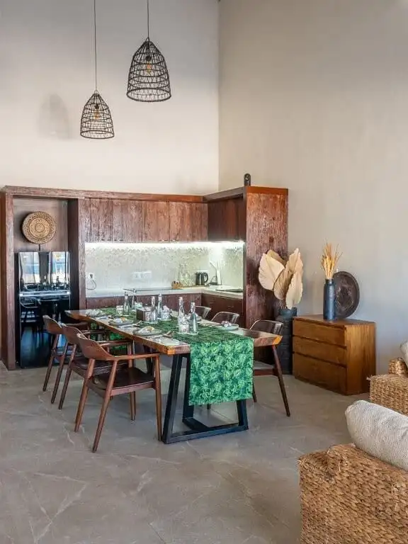 Elegant dining space with wooden furniture, modern lighting, and tropical decor.