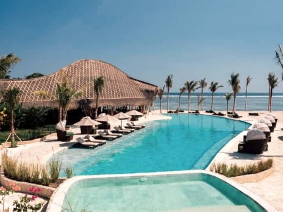 Eco-luxury beachfront resort villas with pool and palm trees in Sumba, Indonesia.
