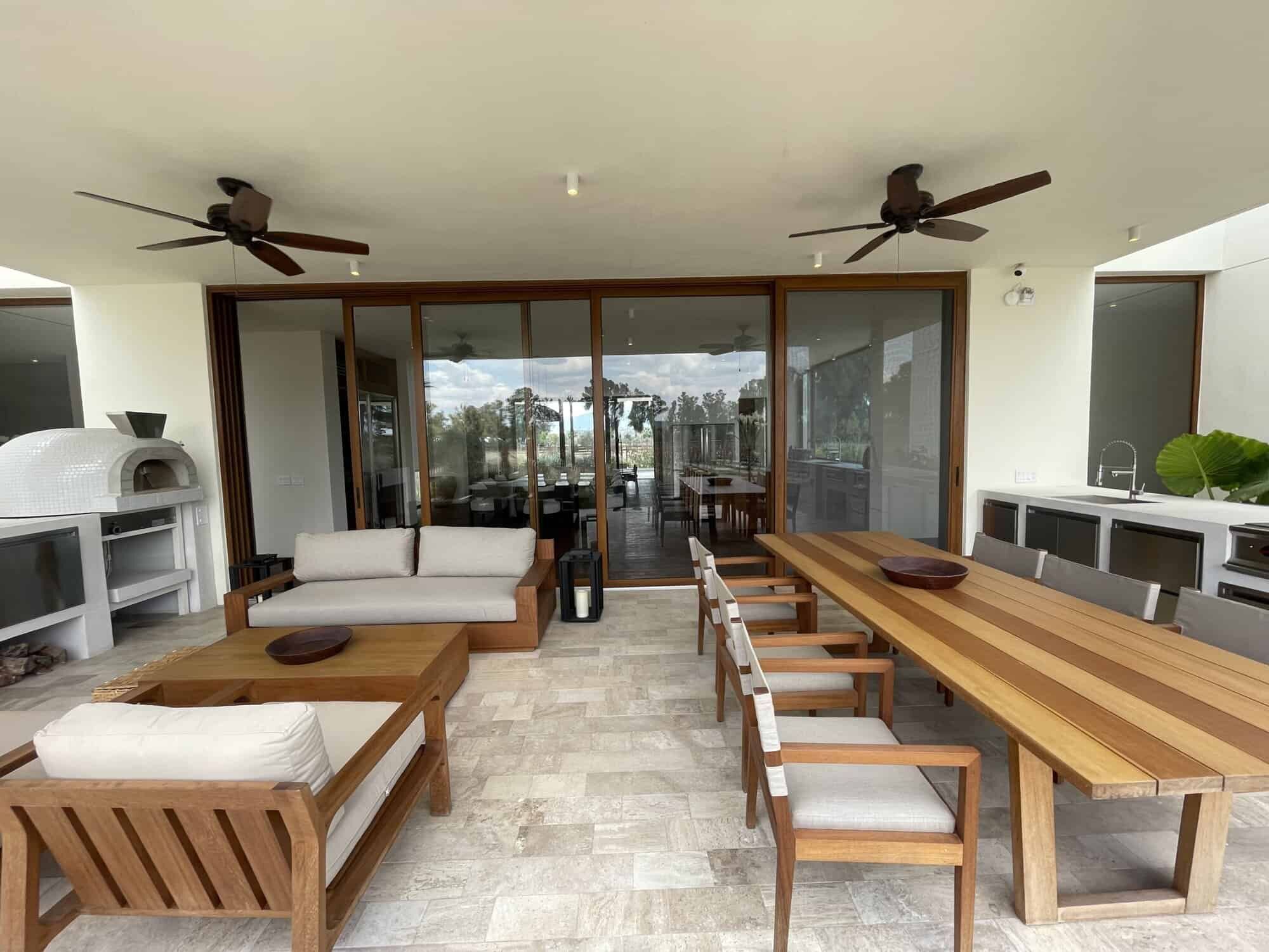 Outdoor living space with wooden furniture, ceiling fans, and panoramic vineyard views.