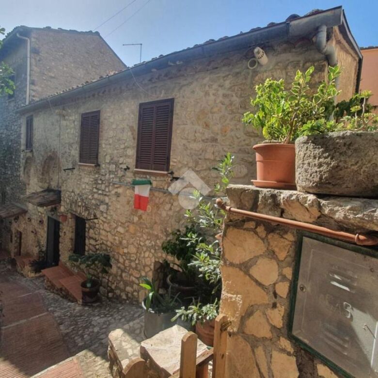House containing 2 apartments for sale in Veroli Lazio, Italy, with stone exterior and lush greenery.