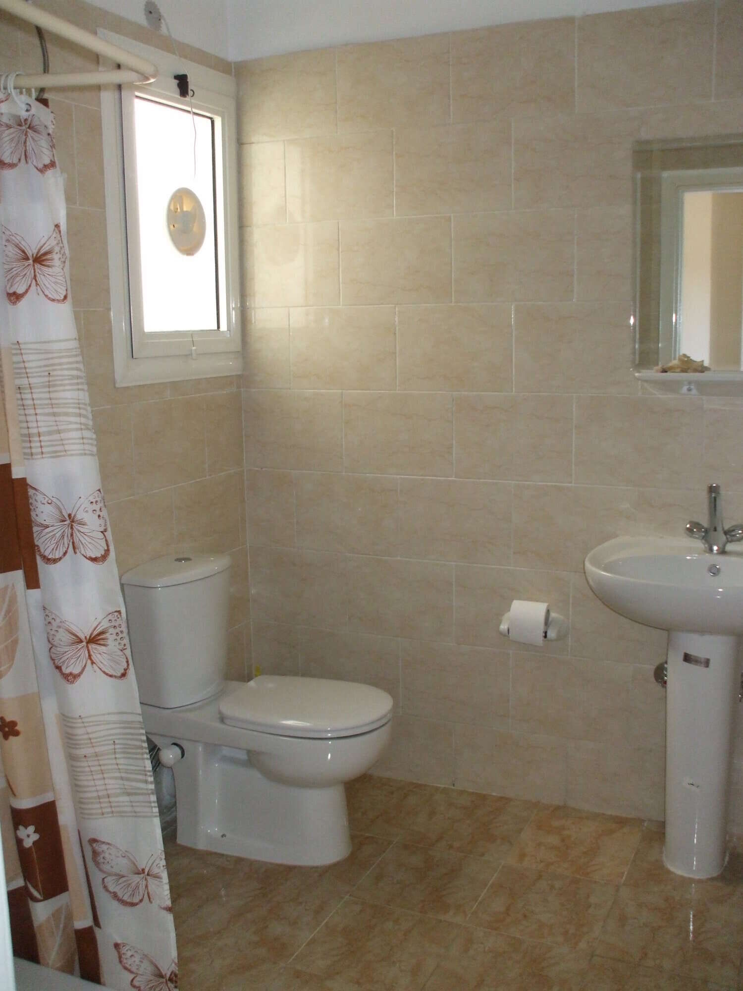 Modern bathroom in Hurghada apartment with neutral tiles and fixtures. Bathroom with toilet, sink, and mirror in a contemporary apartment.