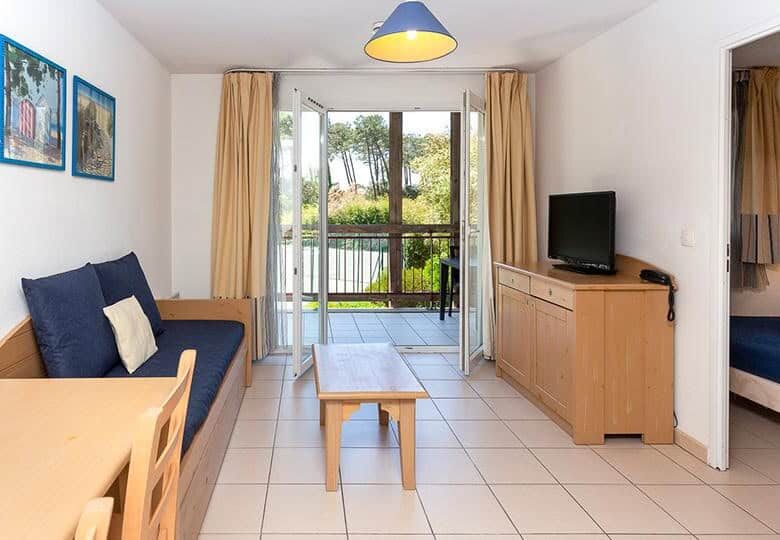 Modern living room with balcony overlooking greenery in a leaseback property in Alle Des Dunes Ondre.