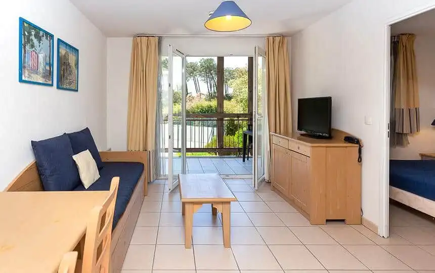 Modern living room with balcony overlooking greenery in a leaseback property in Alle Des Dunes Ondre.