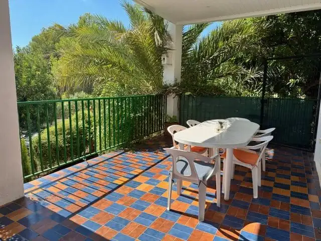 Outdoor terrace with dining area and lush greenery.