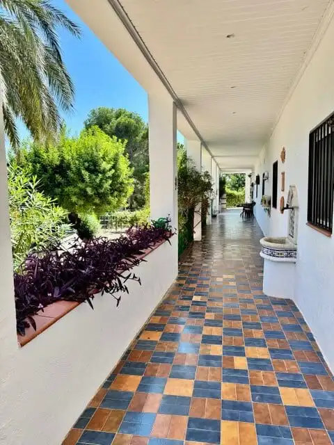 Beautiful covered porch of a 3-bedroom villa in Guadassuar, Valencia, featuring vibrant plants and t.