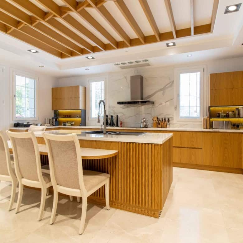 Contemporary kitchen featuring wooden cabinets, a central island, and large windows for natural ligh.