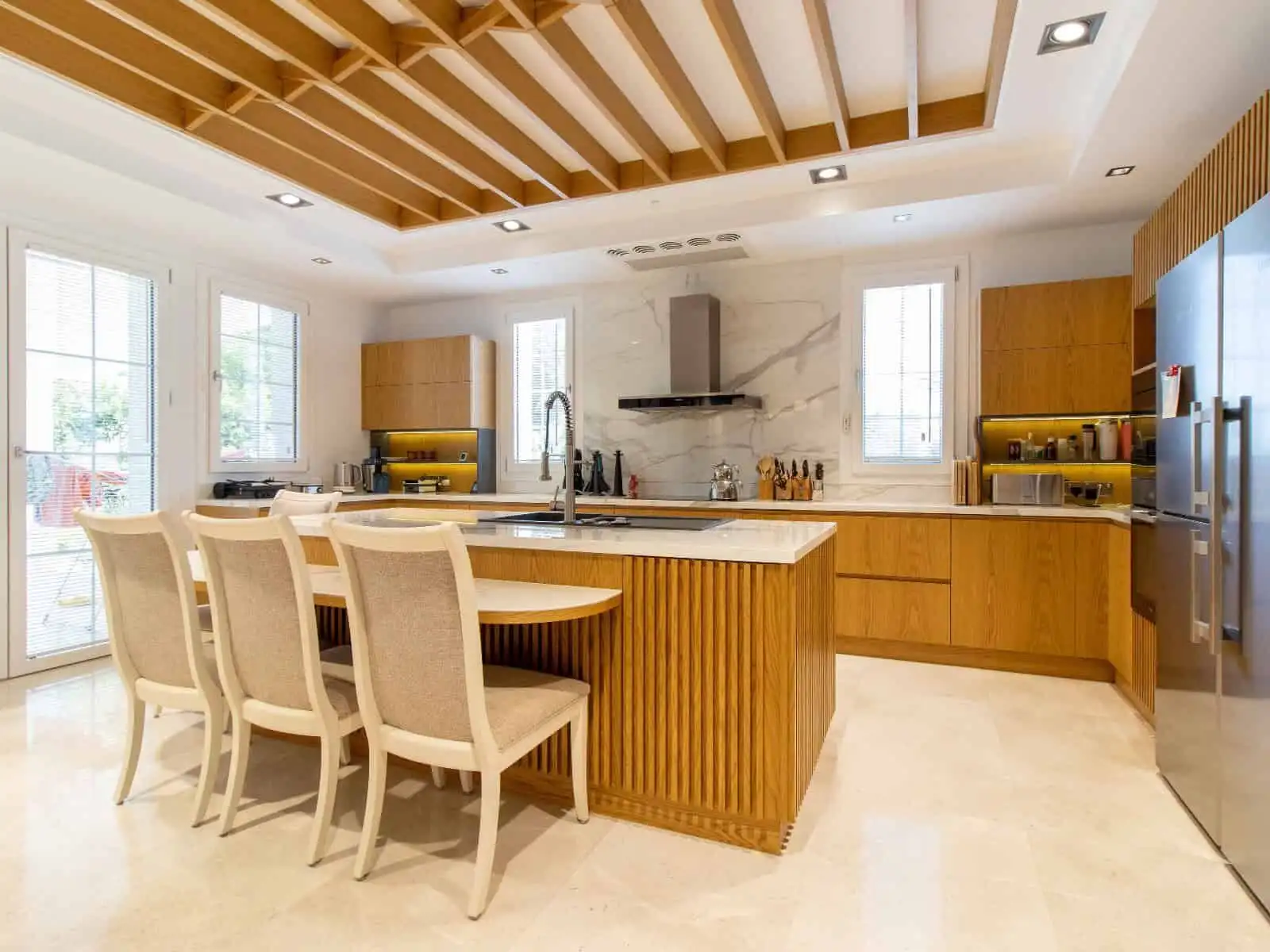 Contemporary kitchen featuring wooden cabinets, a central island, and large windows for natural ligh.