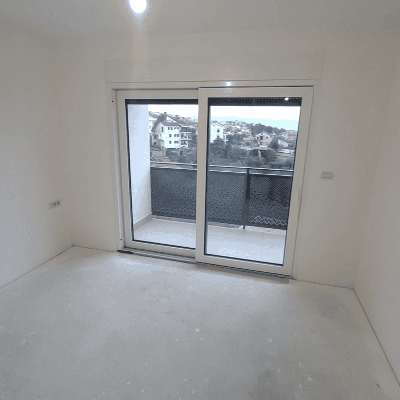 Bright empty room with large glass door leading to balcony in Kvarner duplex.
