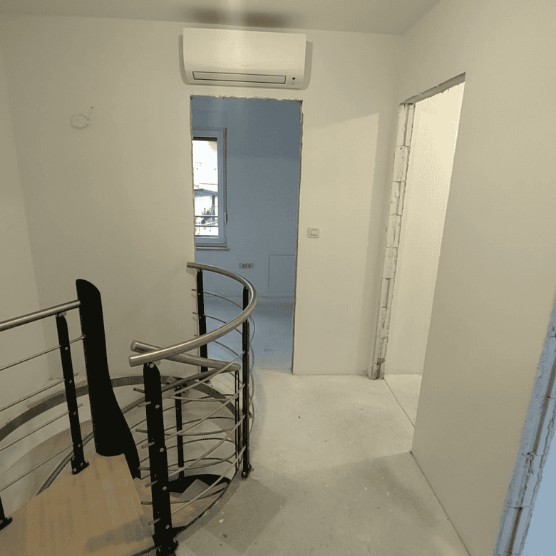 Interior view of a modern duplex in Kvarner, near Rijeka, with staircase and minimal decor.