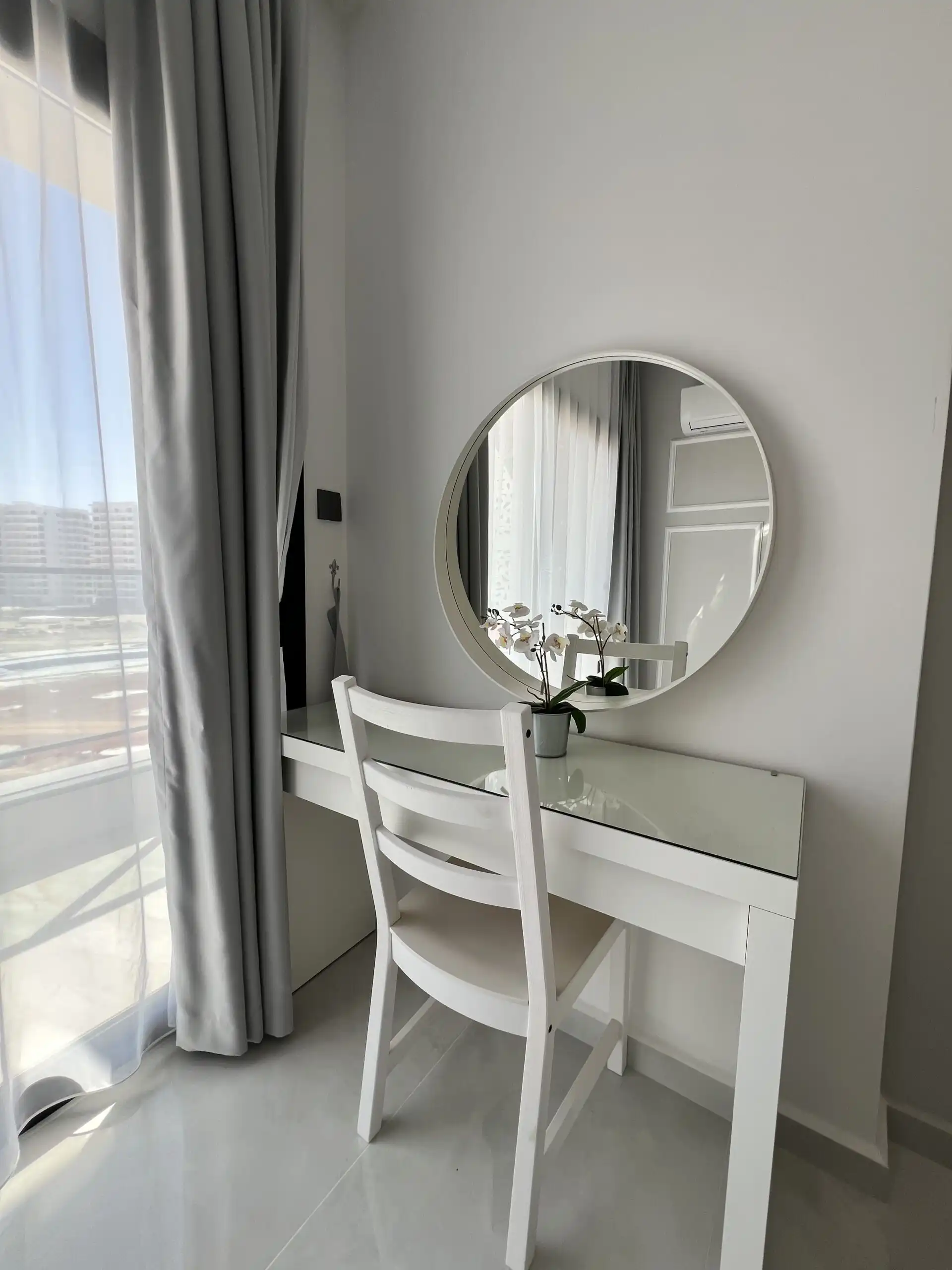 Elegant bedroom vanity with mirror and chair in Caesar Resort apartment.