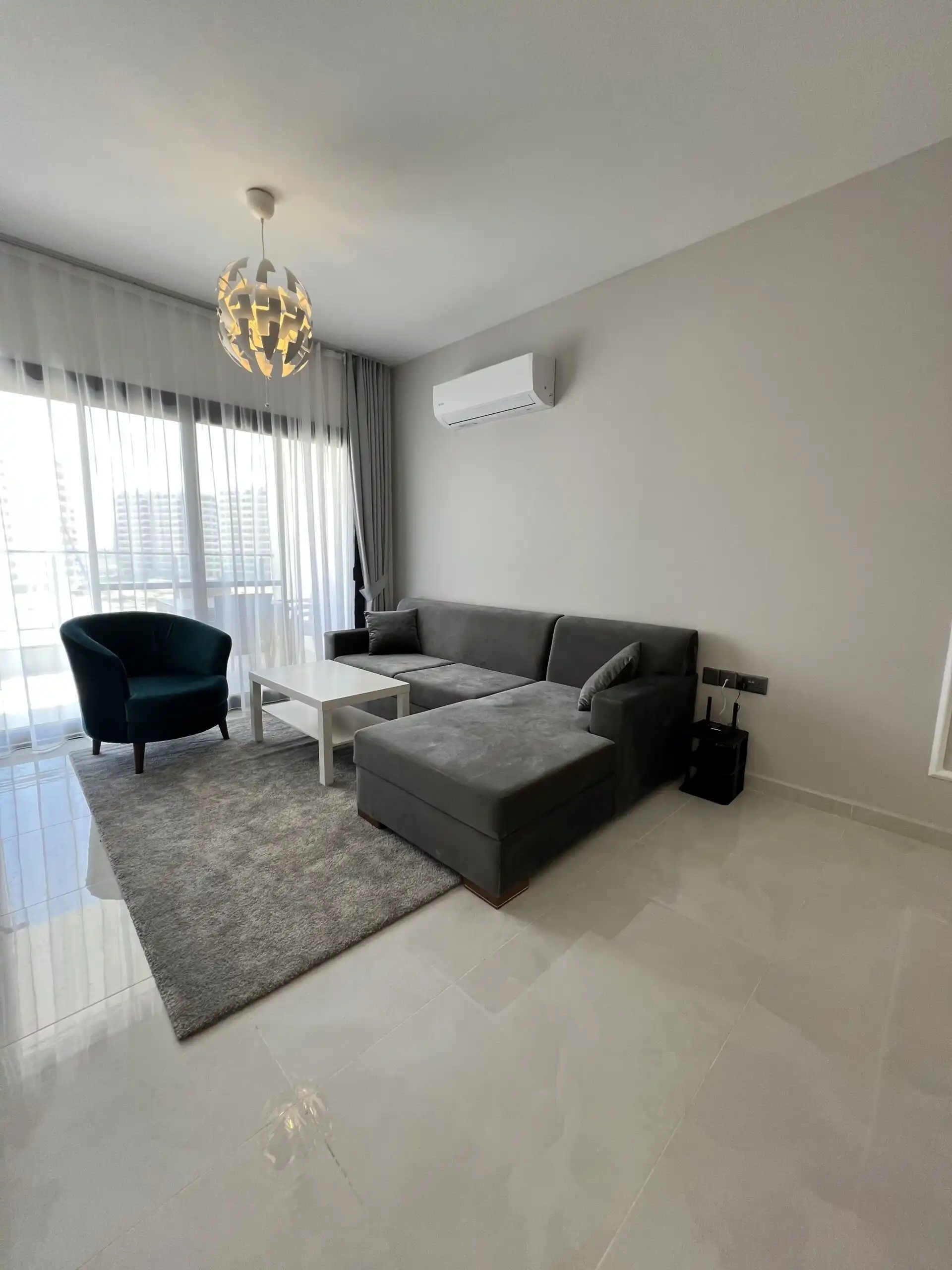 Spacious living room with sofa, armchair, and large window in Caesar Resort, Iskele.
