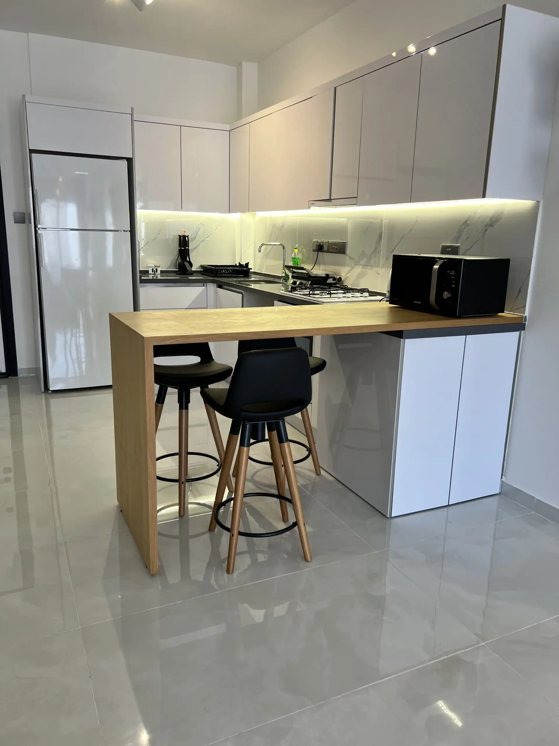 Modern kitchen with white cabinets and a breakfast bar in Caesar Resort, Iskele.