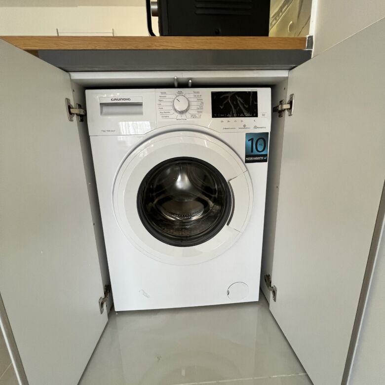 Compact washing machine in Caesar Resort apartment.