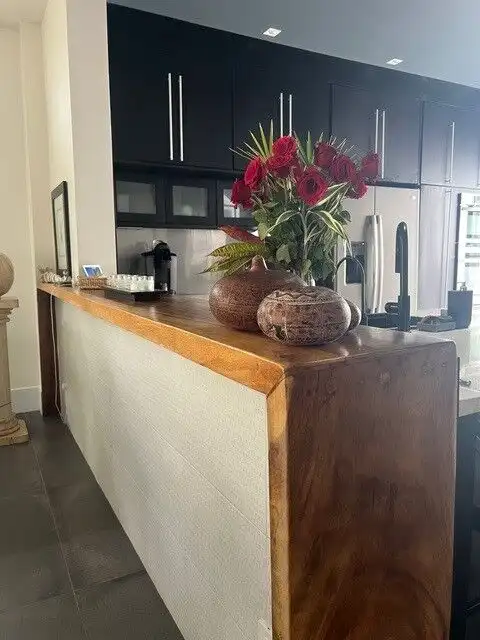Elegant interior with a wooden counter and floral decor in a modern villa.