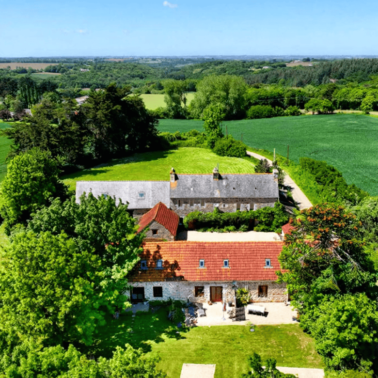 Beautiful rural estate with multiple gites for sale in Runan, Brittany, set amidst lush green fields.