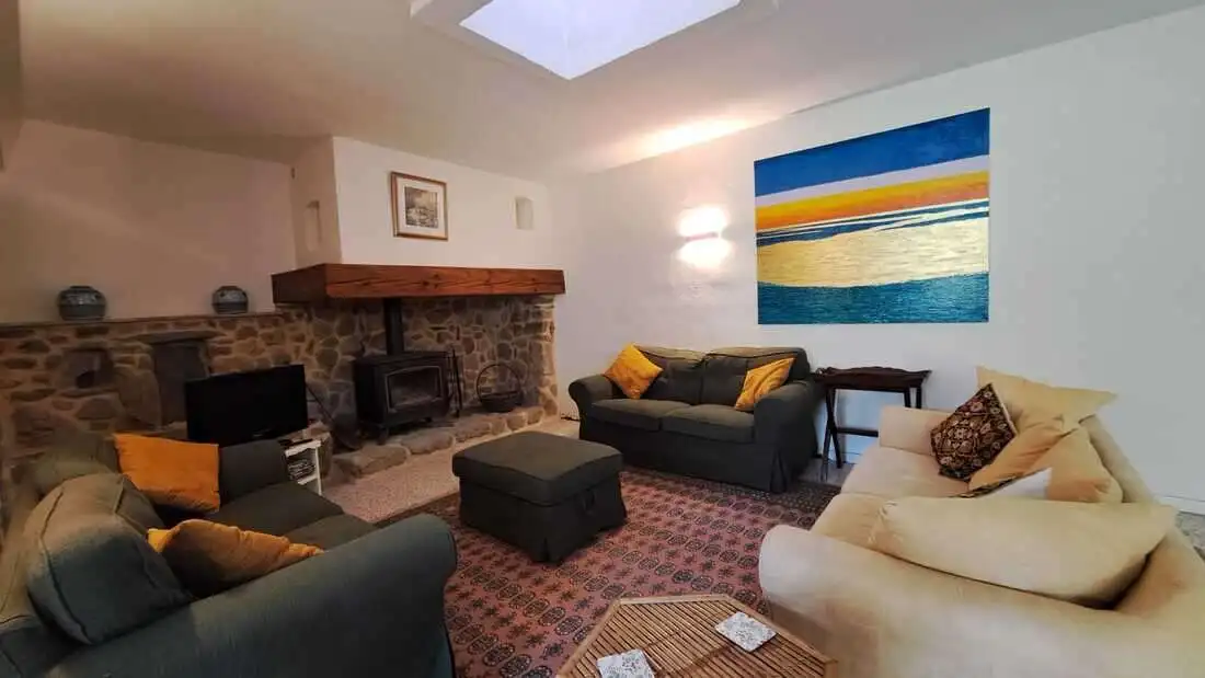Cozy living room with modern furnishings and a stone fireplace. Bright space with colorful artwork a.