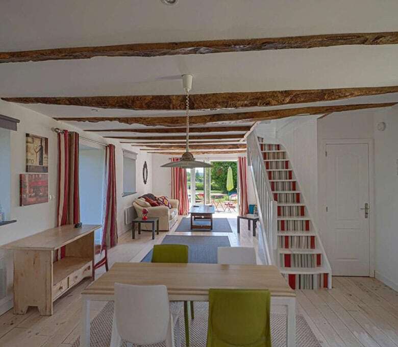 Cozy living space in a Brittany gite with rustic wooden beams and bright decor. Perfect for a peacef.