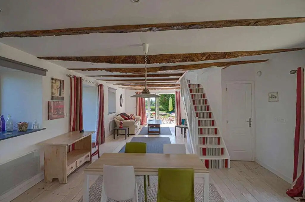 Cozy living space in a Brittany gite with rustic wooden beams and bright decor. Perfect for a peacef.