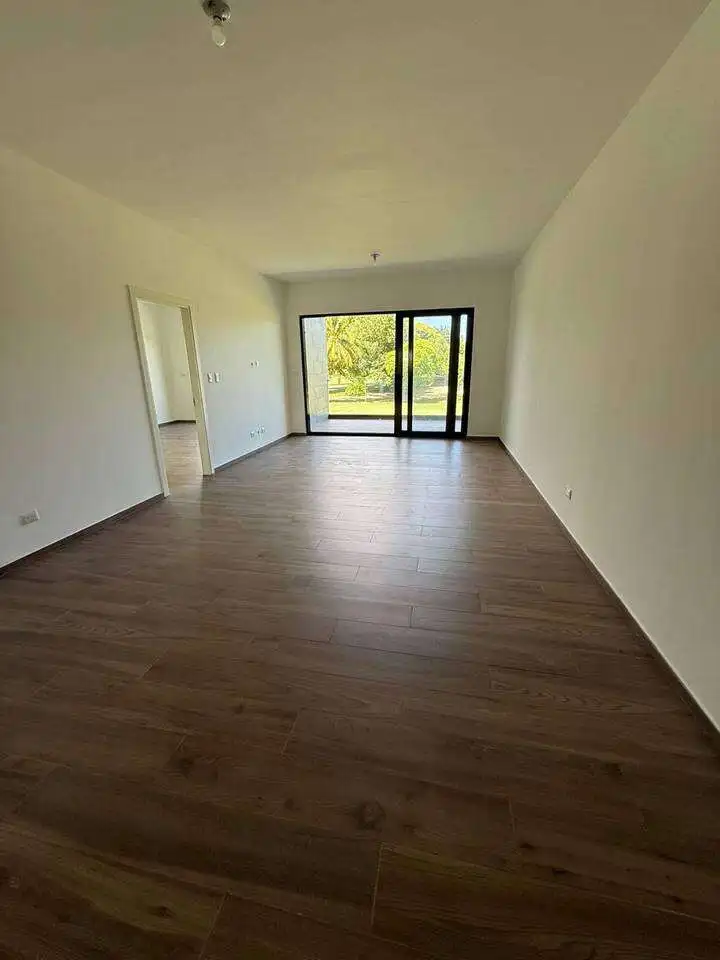 Spacious living room with large glass doors opening to outdoor views in Punta Cana. Modern design pe.