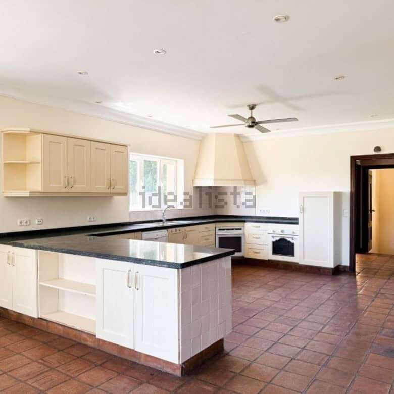 Spacious kitchen with modern cabinets and black countertops in a stunning villa for sale.