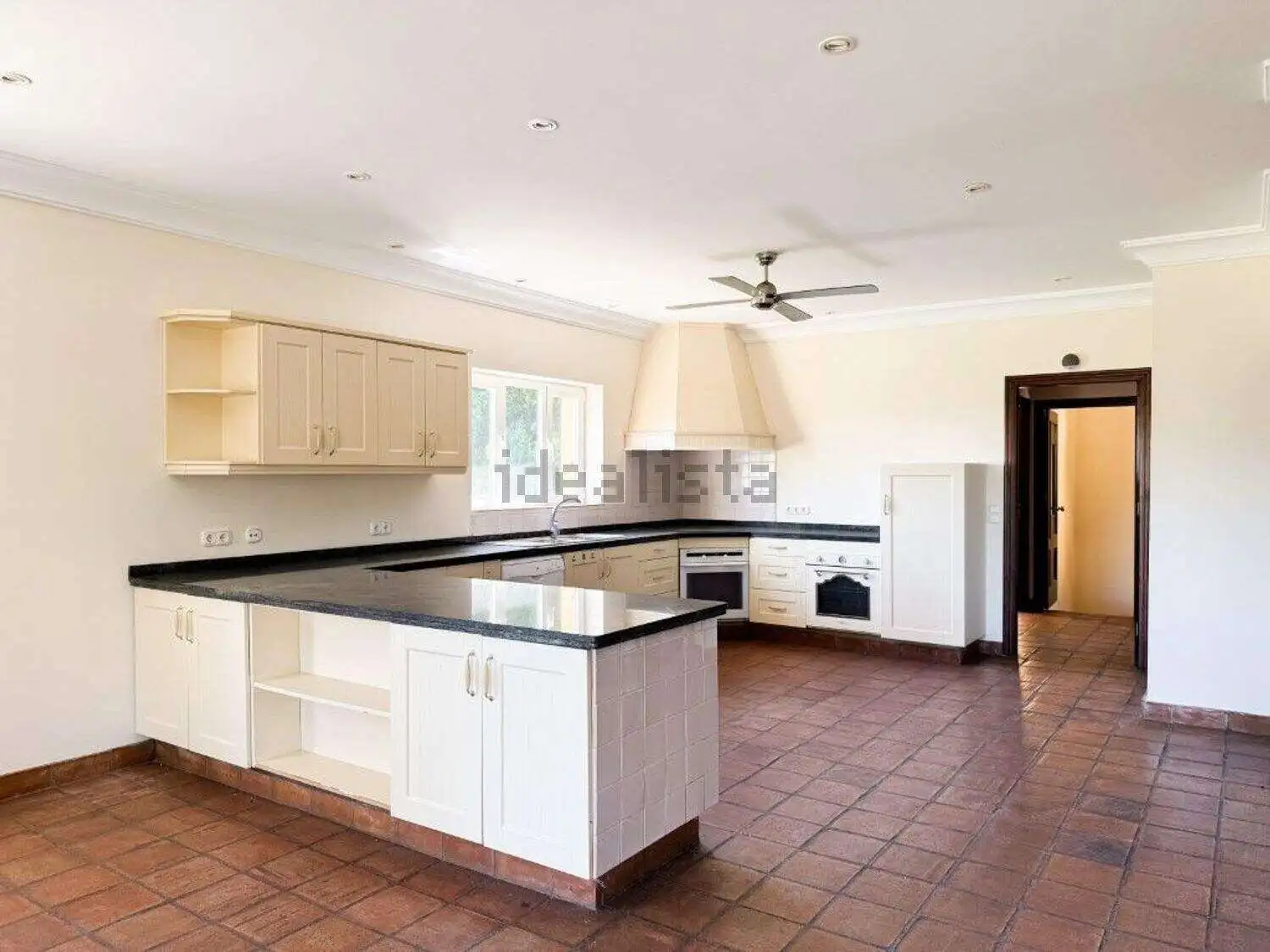 Spacious kitchen with modern cabinets and black countertops in a stunning villa for sale.