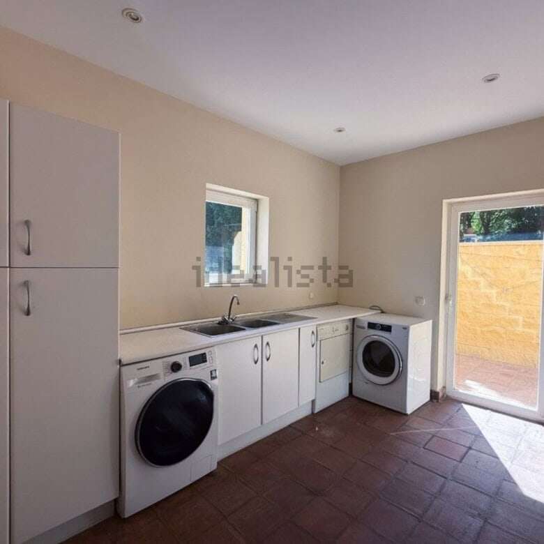 Bright laundry area featuring washing machine, storage cabinets, and access to outdoor space in Soto.