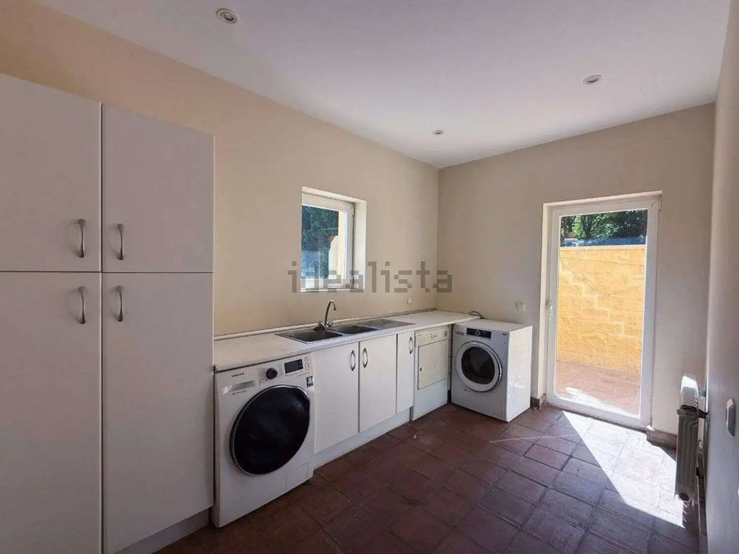 Bright laundry area featuring washing machine, storage cabinets, and access to outdoor space in Soto.