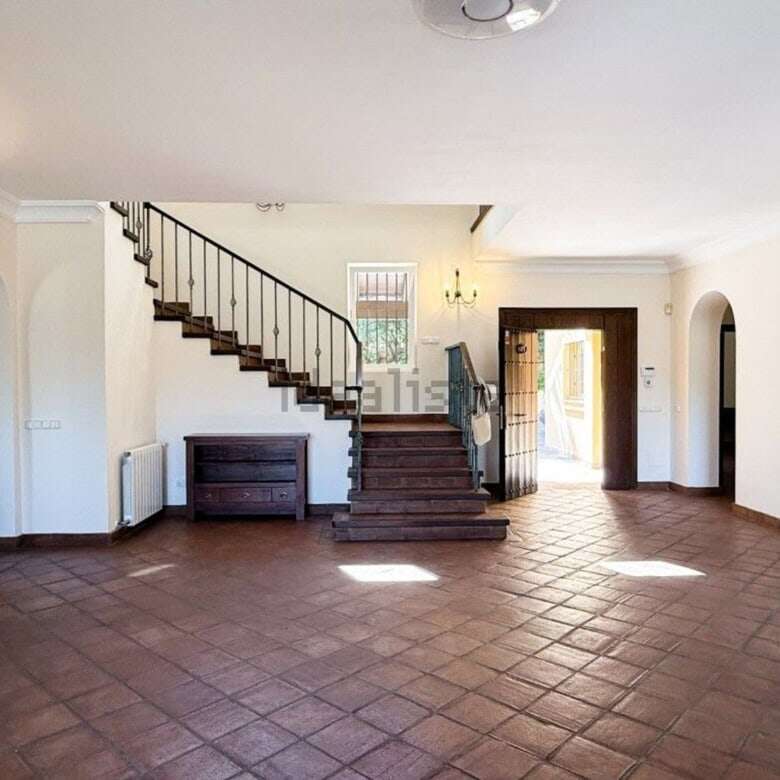 Bright and airy living space with elegant staircase and large windows in Sotogrande villa.