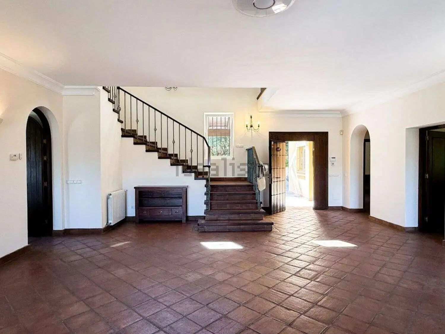 Bright and airy living space with elegant staircase and large windows in Sotogrande villa.