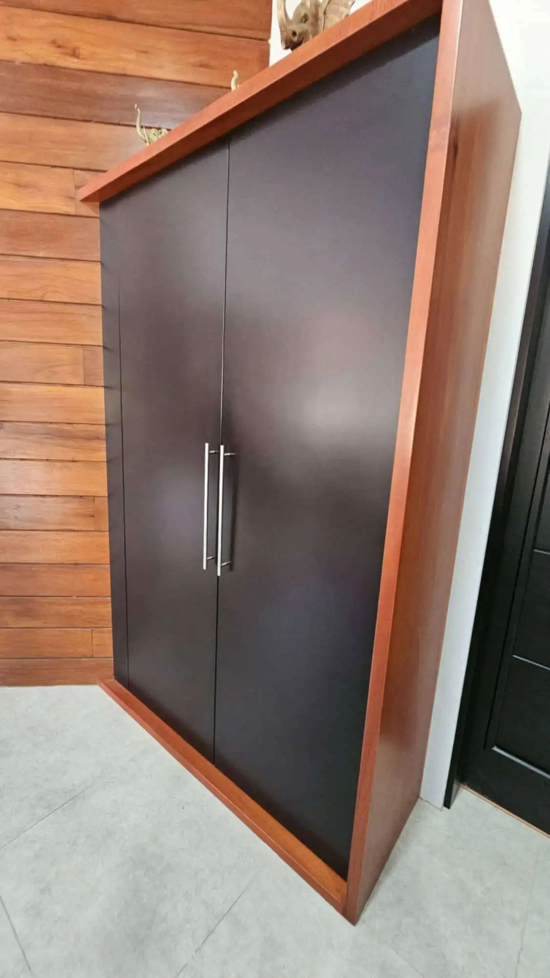 Stylish black and wood storage cabinet with sleek handles, ideal for contemporary home interiors.