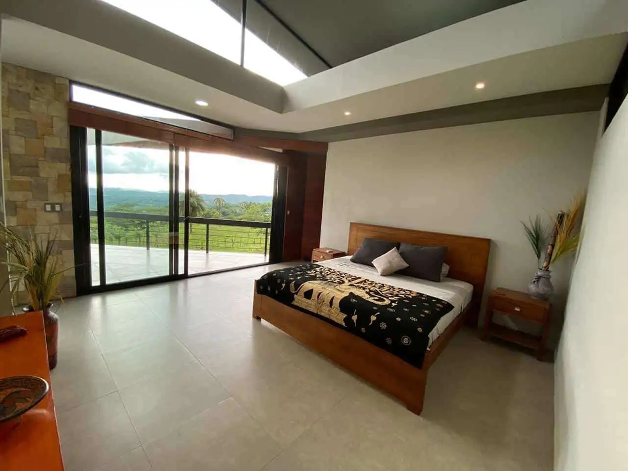 Modern villa bedroom with large glass doors overlooking lush landscape in Miramar de Puntarenas.