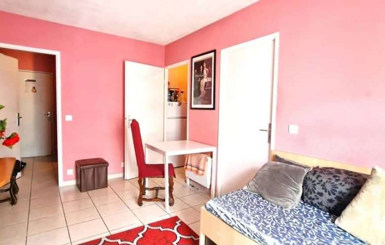 Interior view of a cozy 1-bedroom apartment in Paris with pink walls and modern furnishings.