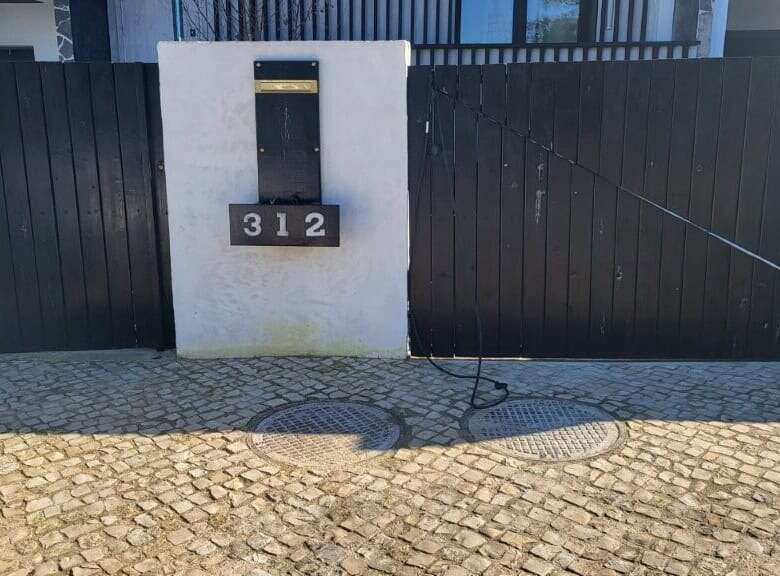 Front view of a modern villa entrance with black gate and house number 312 in Setubal, Portugal.