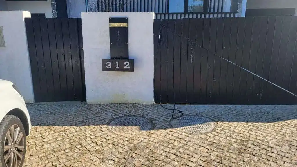 Front view of a modern villa entrance with black gate and house number 312 in Setubal, Portugal.