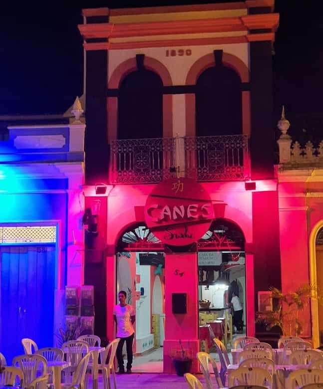 Colonial house in Bahia with vibrant night lighting and outdoor seating.