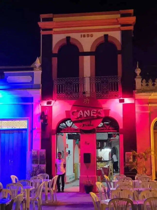 Colonial house in Bahia with vibrant night lighting and outdoor seating.