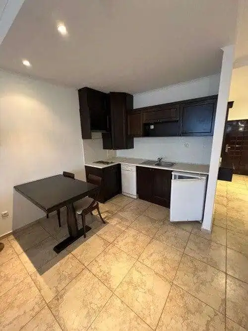 Modern kitchen with dark cabinets and small dining table in a sea view studio apartment.