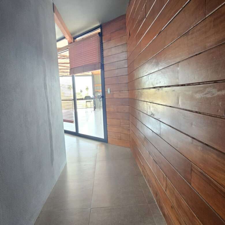 Interior view of a modern villa with wooden wall panels and large glass door in Miramar, Costa Rica.