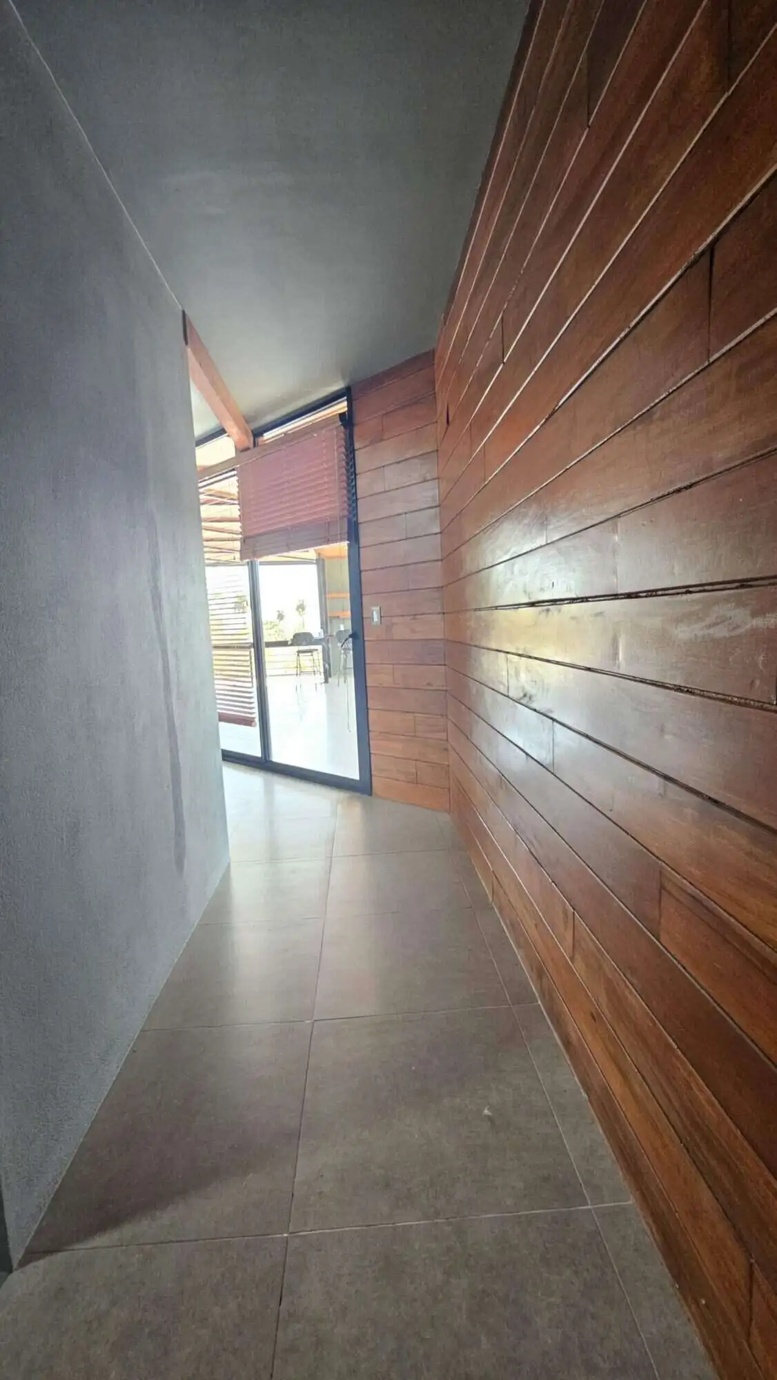 Interior view of a modern villa with wooden wall panels and large glass door in Miramar, Costa Rica.
