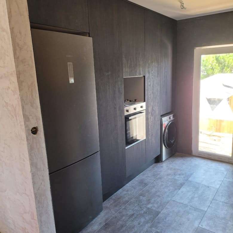 Modern kitchen with built-in refrigerator, oven, and washing machine in a stylish villa.