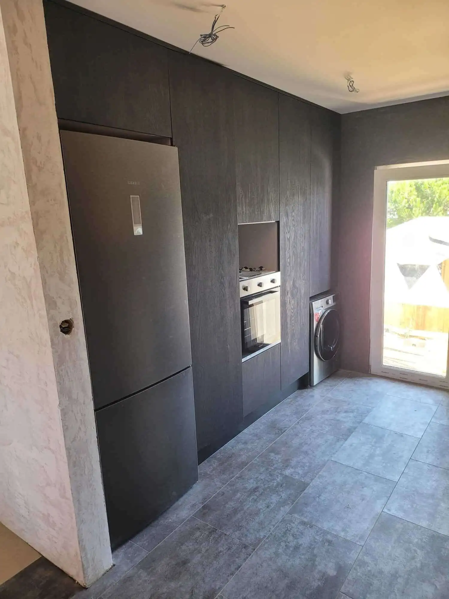 Modern kitchen with built-in refrigerator, oven, and washing machine in a stylish villa.